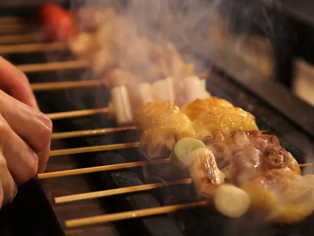 焼鳥店の焼き場で串の焼き加減と提供品質を確認する様子